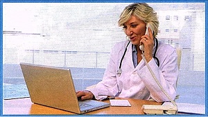 Female Physician sitting at a desk with an open laptop on the table and phone held up to her ear